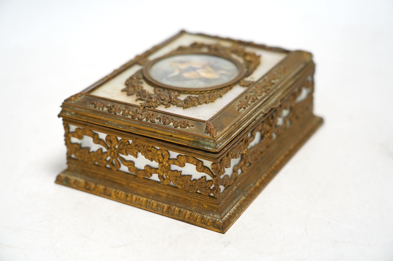 A French mother of pearl and gilt metal trinket box inset with a hand painted panel of two figures, 15cm wide. Condition - fair, feet present (one broken)